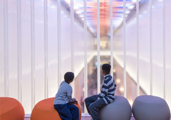 two boys looking out glass window over atrium