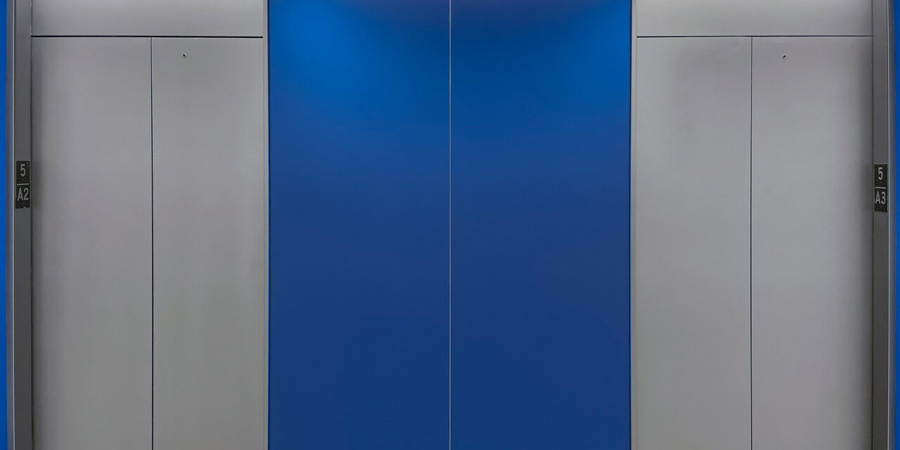 Blue etched glass cladding the walls of the elevator lobby.