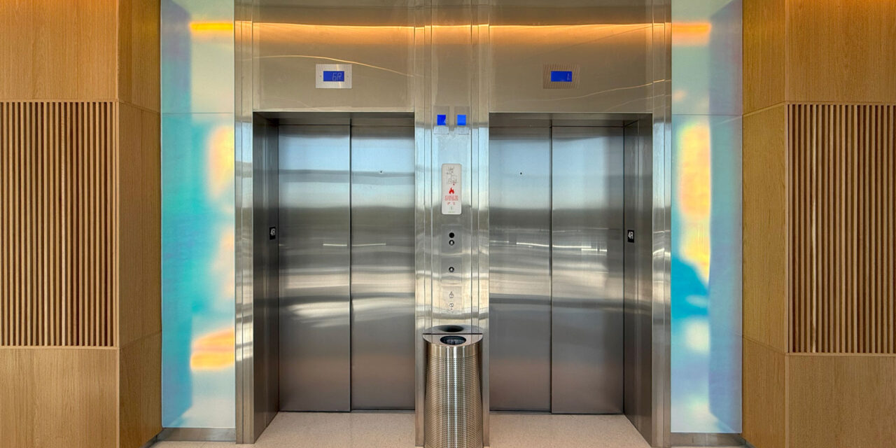 Etched dichroic glass clads the walls around the elevators.