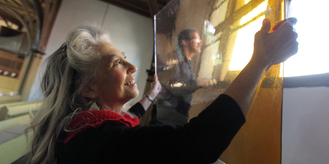 Glass artist holding glass panel.