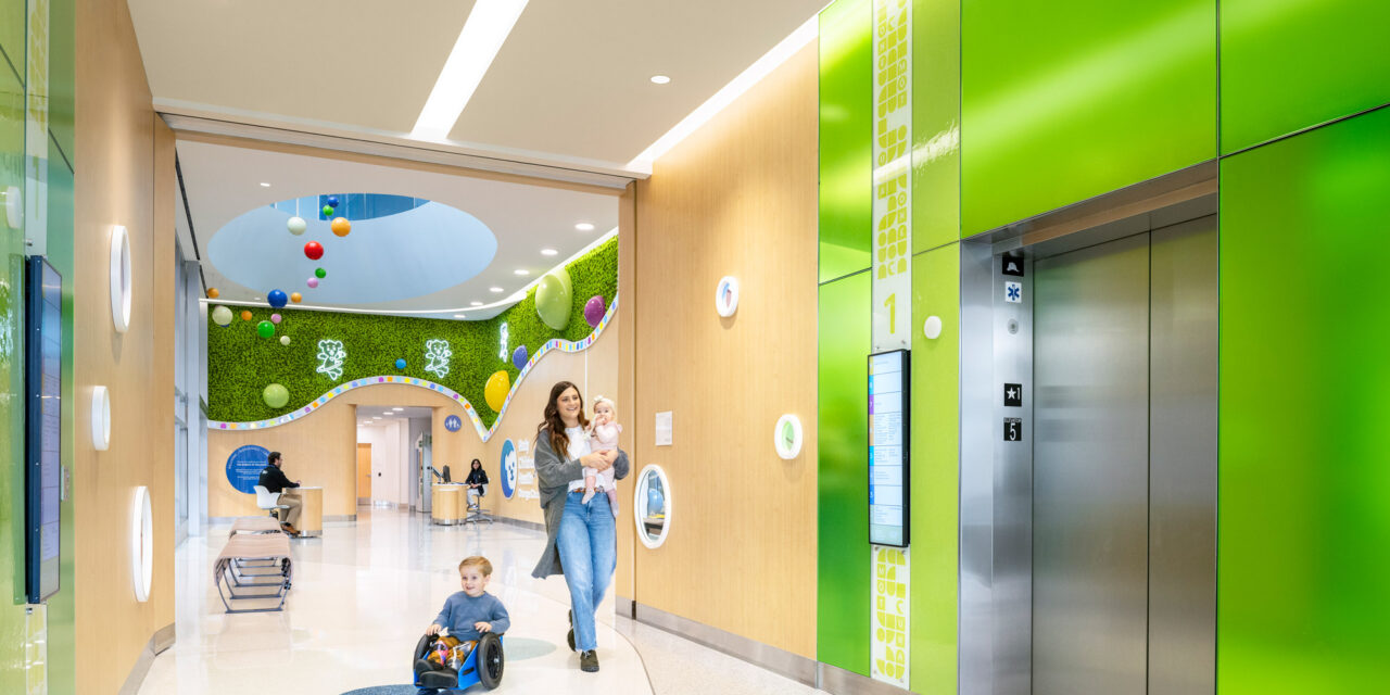 Elevator lobby walls made of colorful Bendheim glass with a child and mother approaching the elevator.