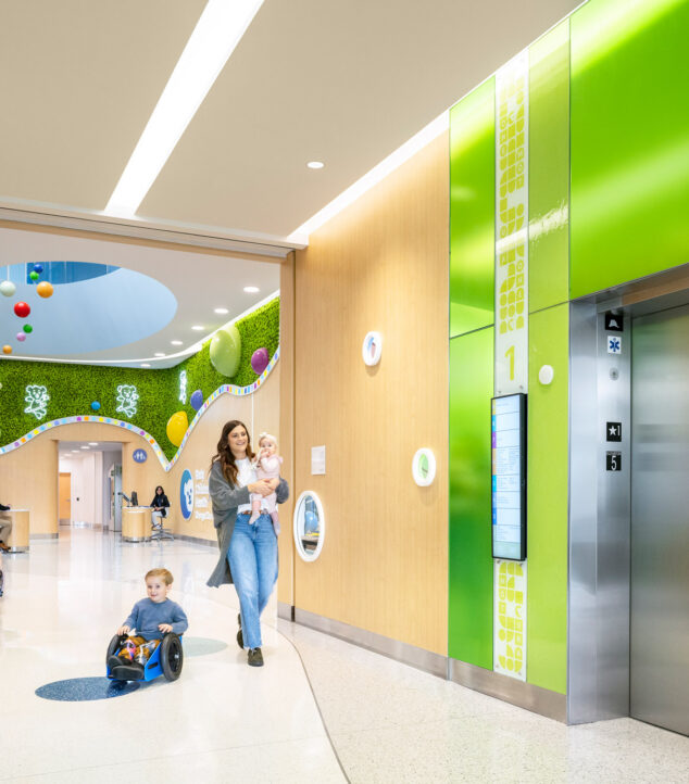 Elevator lobby walls made of colorful Bendheim glass with a child and mother approaching the elevator.