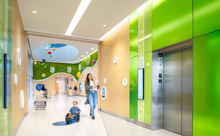 Elevator lobby walls made of colorful Bendheim glass with a child and mother approaching the elevator.