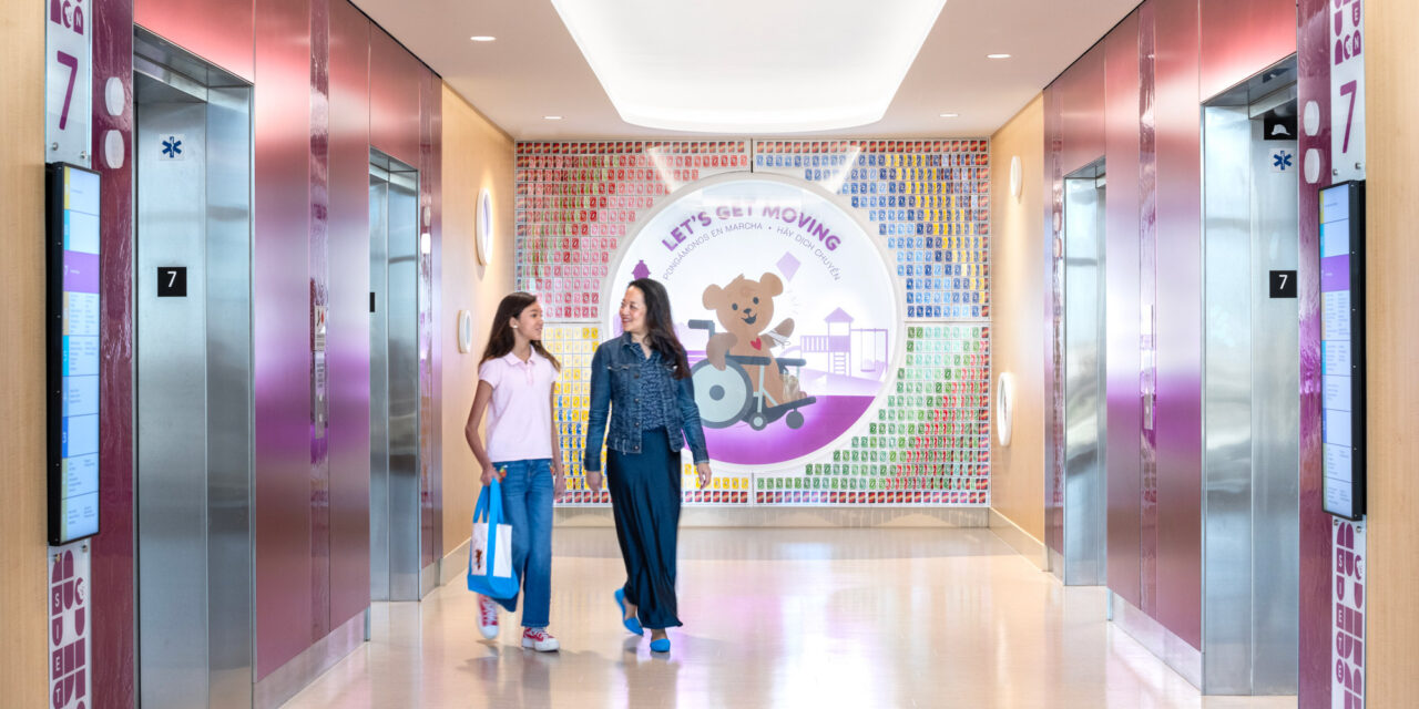 Elevator lobby walls made of colorful Bendheim glass with a child and mother leaving the elevator.