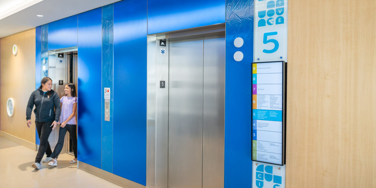 Elevator lobby walls made of colorful Bendheim glass with a child and mother leaving the elevator.