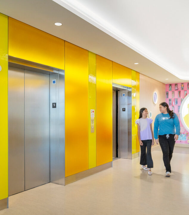Elevator lobby walls made of colorful Bendheim glass with a child and mother leaving the elevator.