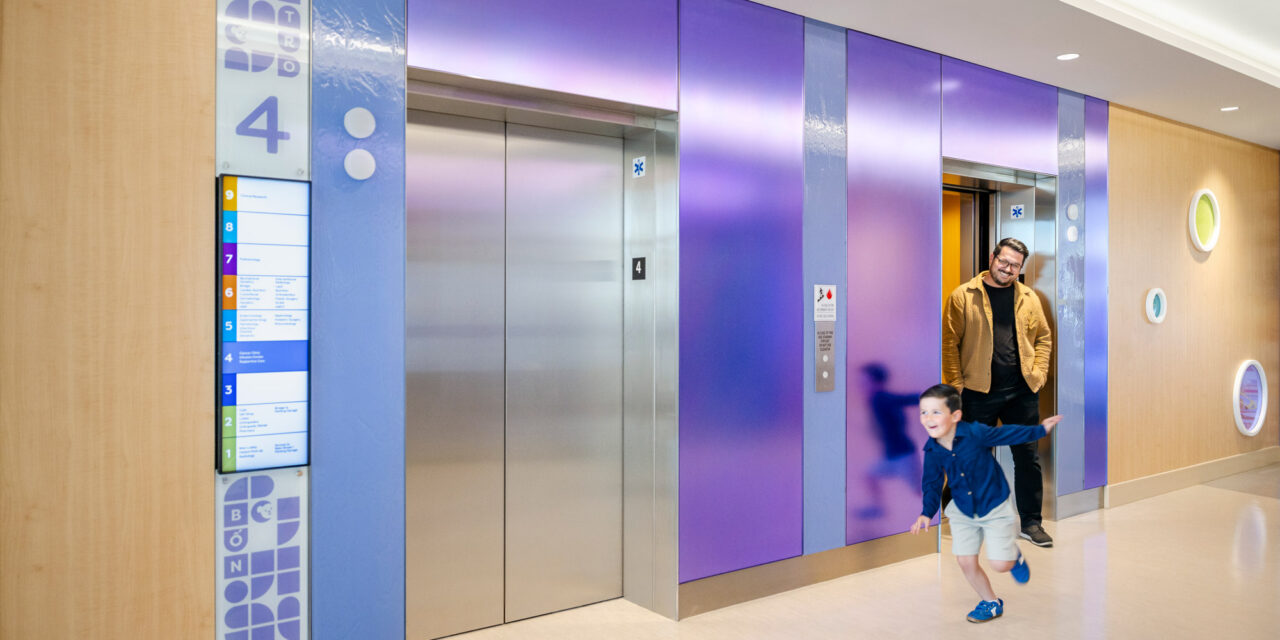 Elevator lobby walls made of colorful Bendheim glass with a child and father leaving the elevator.