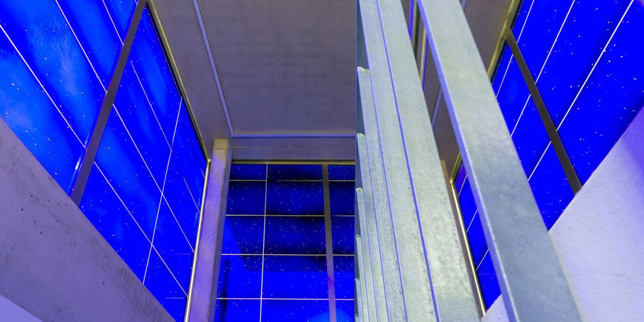 Blue mouth-blown glass enclosing a stairwell.
